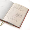 Open guided wellness journal with lined pages by Floral Ikat, showing handwriting and a page marker.