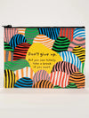 Zipper pouch by Blue Q with colorful striped hills and a yellow text bubble that reads "Don't give up."
