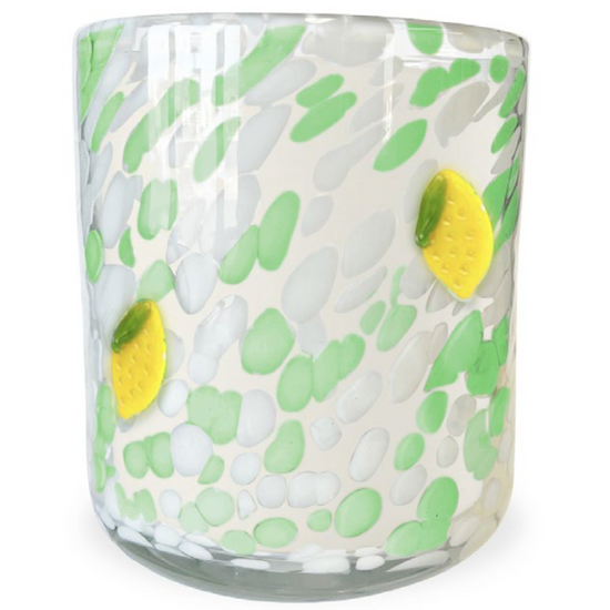 Scented candle with a white wax fill, decorated with green and white spots and yellow lemon accents.