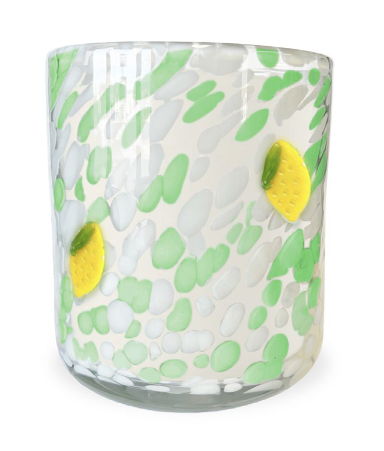 Scented candle with a white wax fill, decorated with green and white spots and yellow lemon accents.