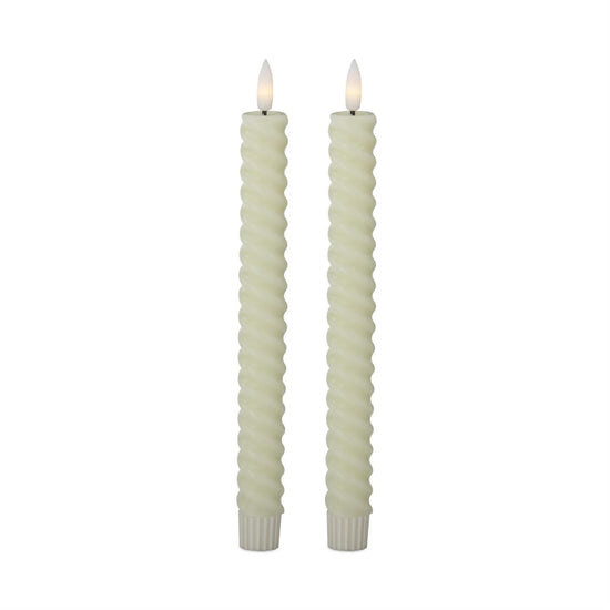 Two twisted candles with white wicks on a white background