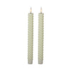 Two twisted candles with white wicks on a white background