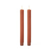 Two brown textured candles on a white background