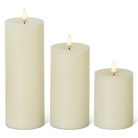 Three cream-colored candles of different sizes on a white background