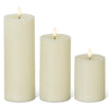 Three cream-colored candles of different sizes on a white background