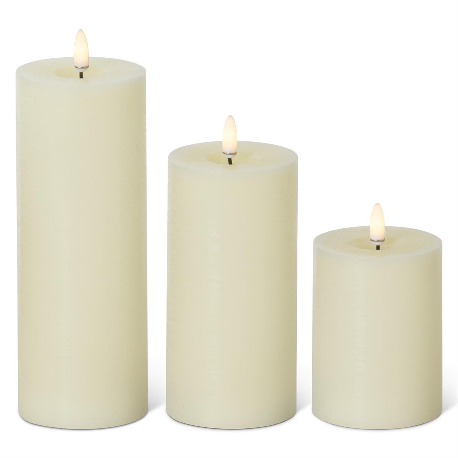 Three cream-colored candles of different sizes on a white background
