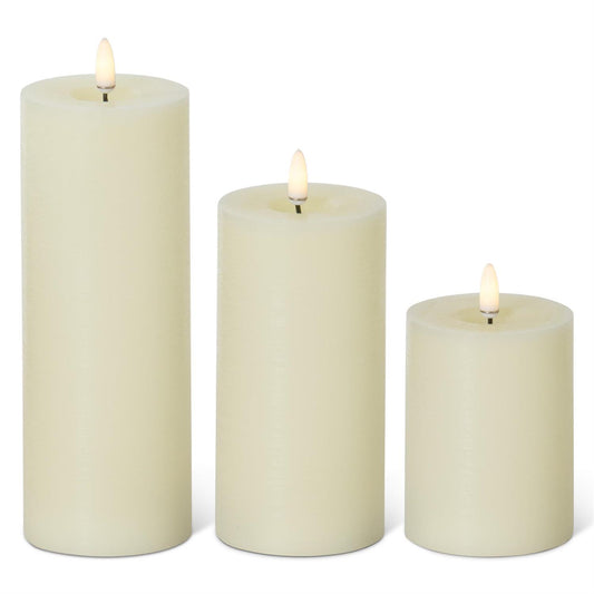 Three cream-colored candles of different sizes on a white background