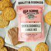Snickerdoodle cookie mix by Old School Brand, with cinnamon sugar packet, surrounded by baked cookies on a serving board.
