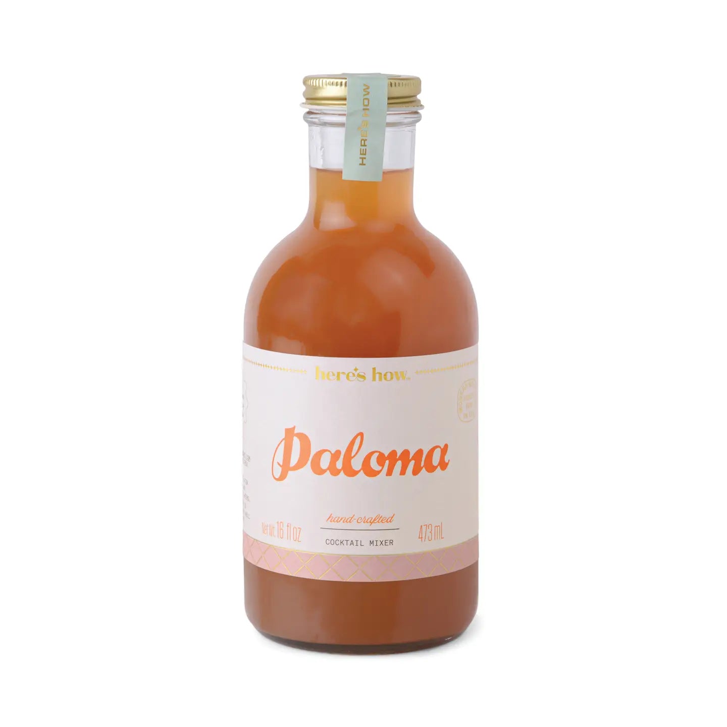 Paloma cocktail mixer from Here's How, in a clear glass bottle with a gold lid and label.
