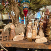 Wooden nativity set with burlap by an unknown brand, arranged on a wooden surface with paper Christmas trees.
