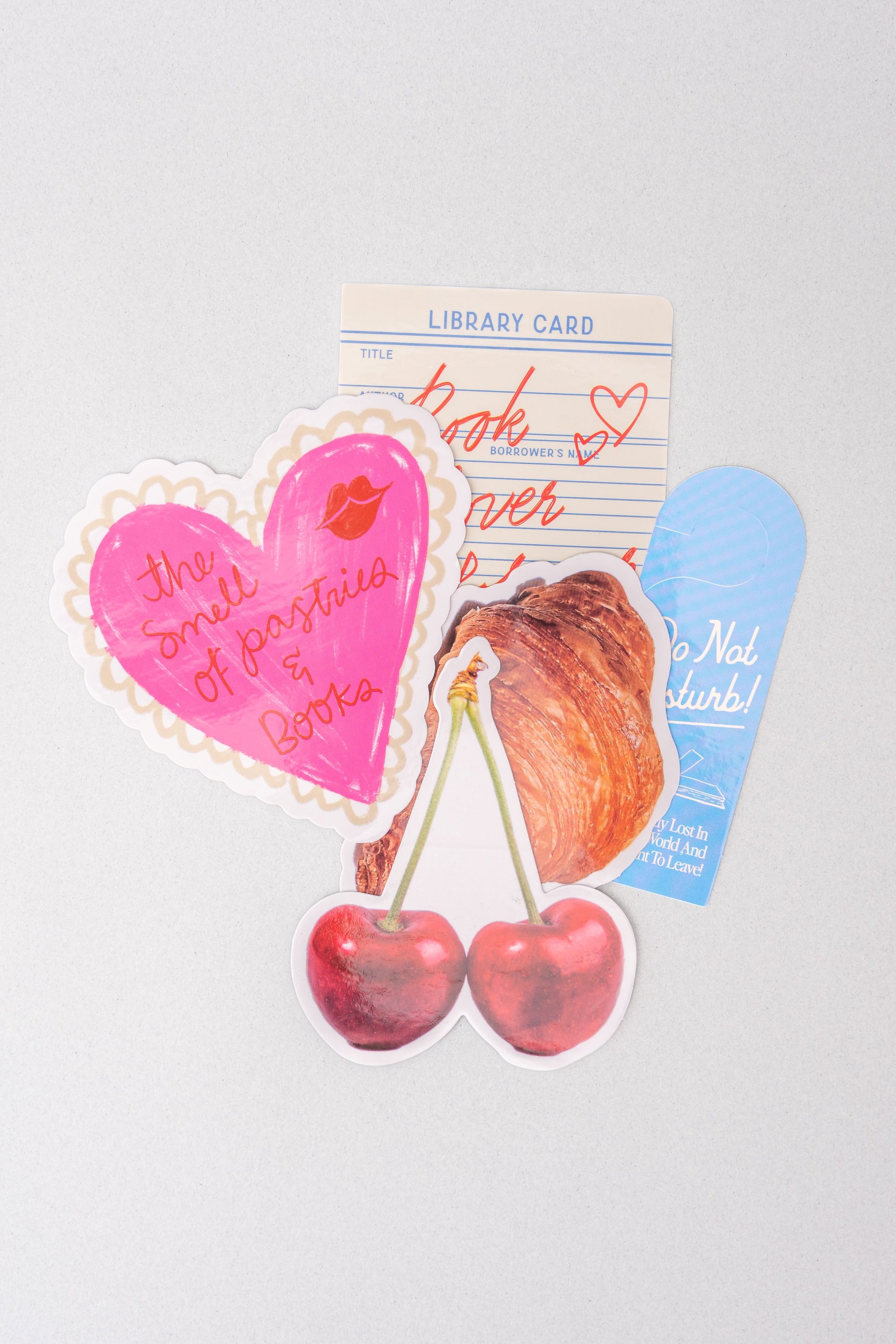Assorted stationery stickers with library card, heart, cherries, and croissant designs.