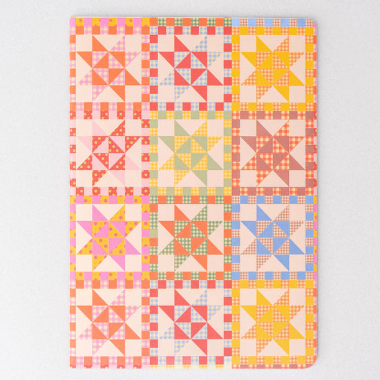 Set of three stationery notebooks with colorful quilt pattern detail.