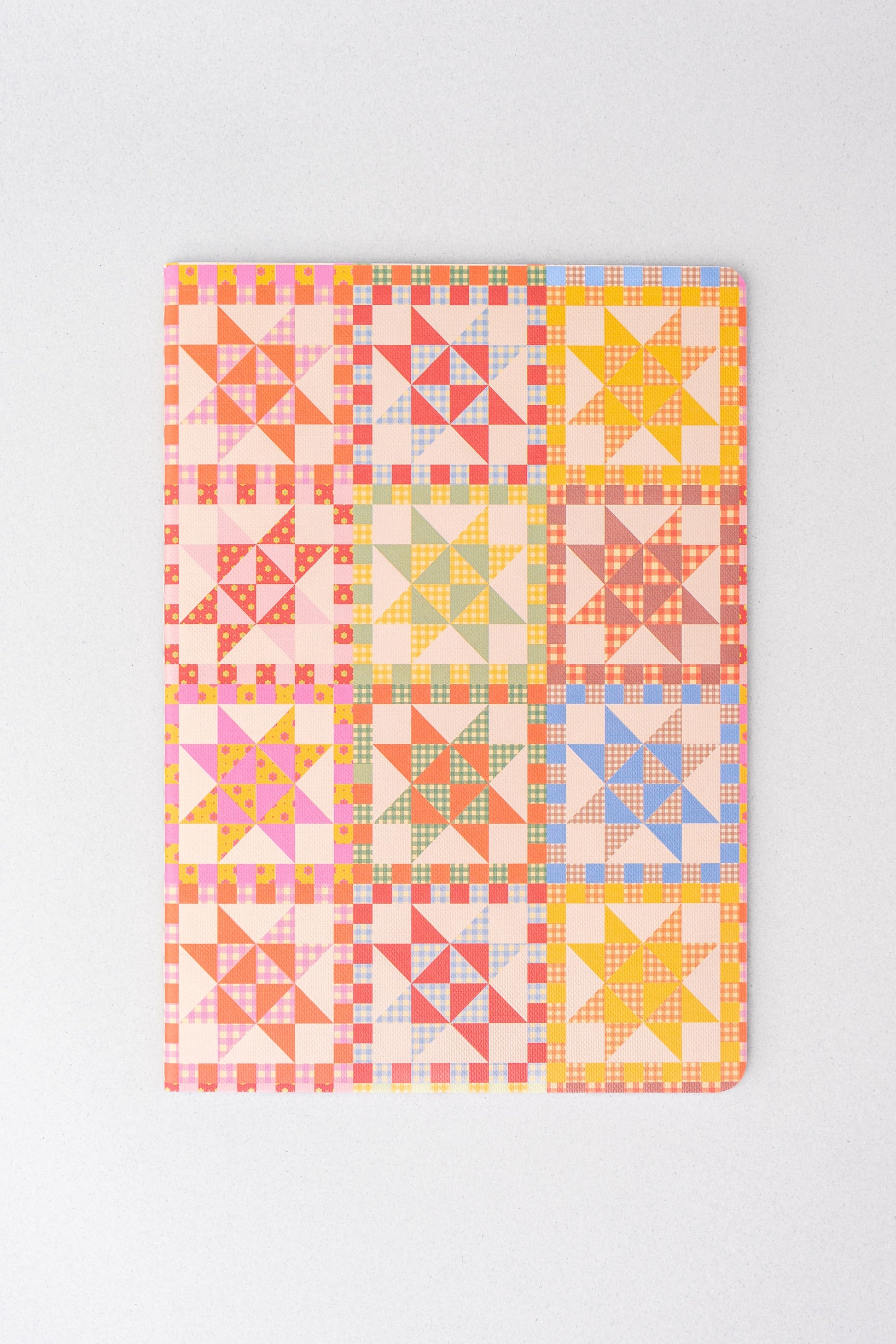 Set of three stationery notebooks with colorful quilt pattern detail.