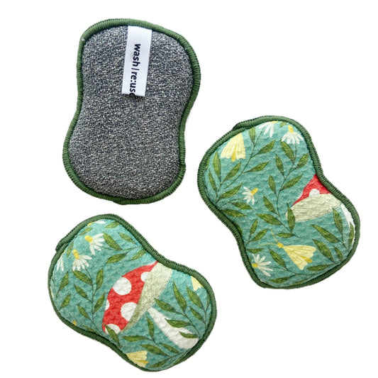 Set of three reusable sponges with green trim, from Undergrowth Herb, one grey and two with floral and mushroom pattern.
