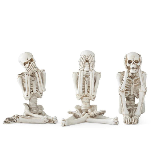 Three skeleton figurines in various poses on a white background