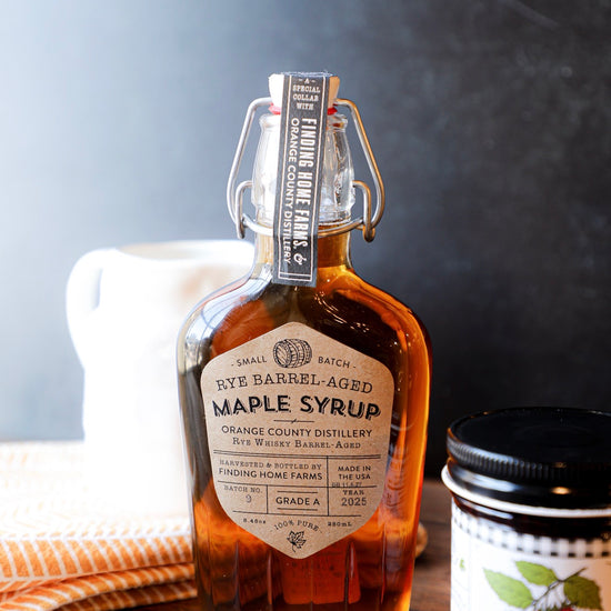 Rye barrel-aged maple syrup in a swing top bottle by Finding Home Farms with a barrel symbol and decorative label.