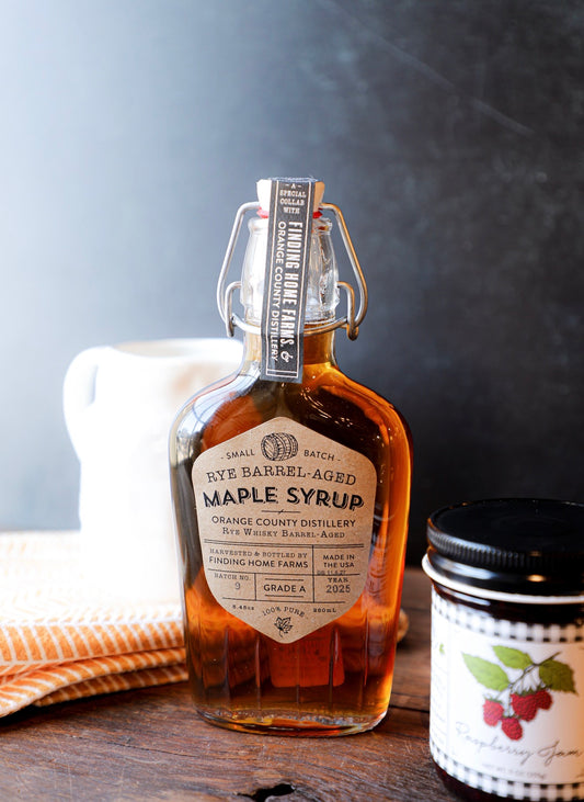 Rye barrel-aged maple syrup in a swing top bottle by Finding Home Farms with a barrel symbol and decorative label.