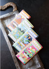 Colorful chocolate truffle bars by Maeve, stacked on a decorative silver tray with a textured handle.
