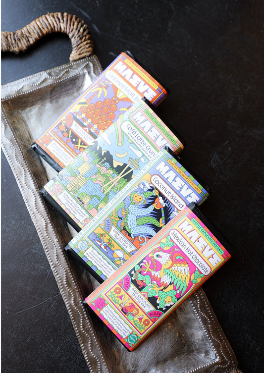 Colorful chocolate truffle bars by Maeve, stacked on a decorative silver tray with a textured handle.
