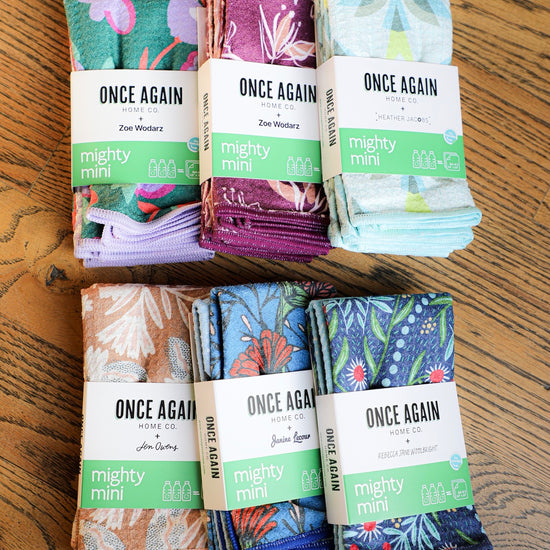 Reusable patterned towels by Once Again + stacked on a wooden table with reversible microfiber cloths.