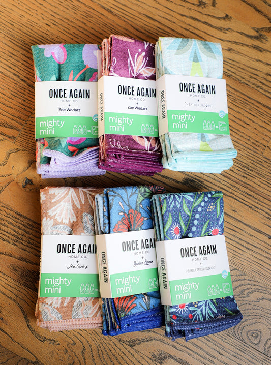Reusable patterned towels by Once Again + stacked on a wooden table with reversible microfiber cloths.