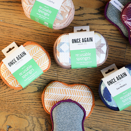 Reusable sponges by Once Again Home Co. in various patterns and colors on a wood surface.
