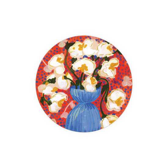 Circular, vibrant art coaster featuring white flower blossoms by unknown artist in a blue vase against red polka dot background.