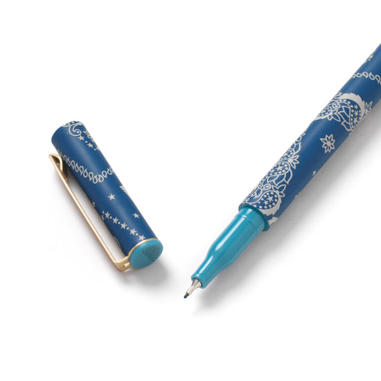 Stationery pen with a blue barrel by Solstice, featuring a white bandana pattern, next to a cap.