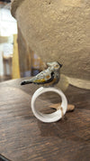 White stoneware napkin ring with a ceramic bird by Creative Co-op, resting on a wood surface.