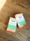Set of orange and white reusable paper towels by Once Again, displayed on a wooden surface.