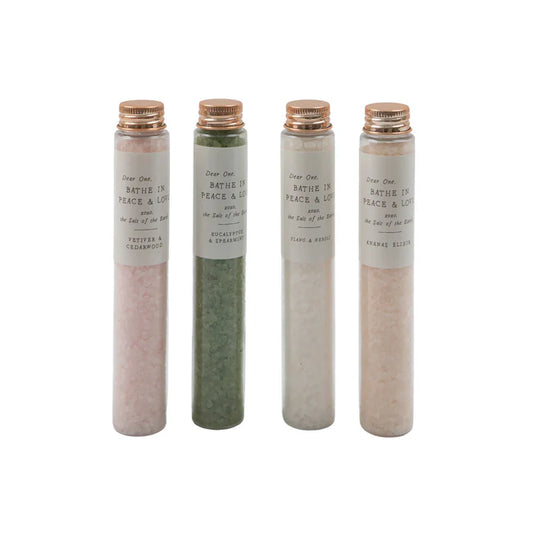 Four bath salt vials with copper lids filled with different colored salts.