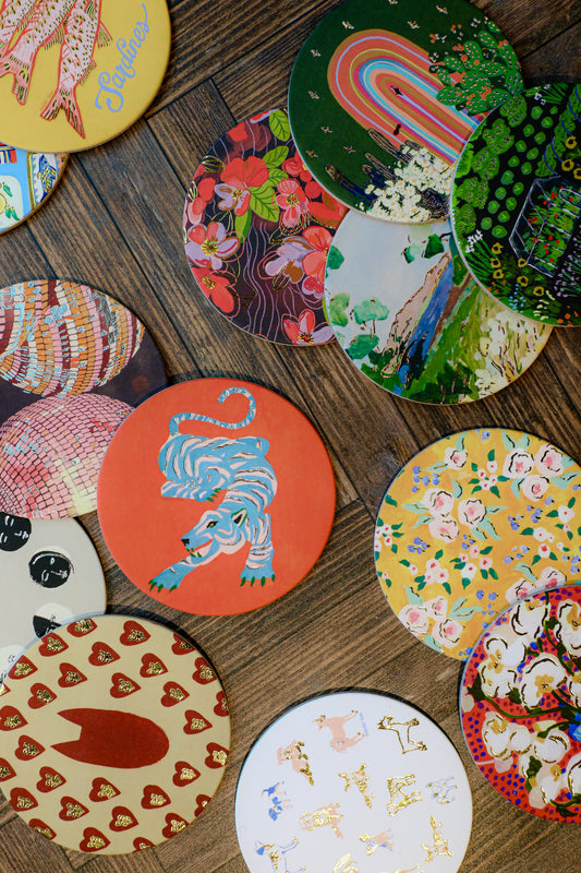 Set of decorative coasters by Seedlings with colorful patterns and artful designs on a wood surface.