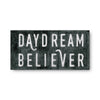 Black and white art tiles with 'Daydream Believer' text, featuring weathered texture.
