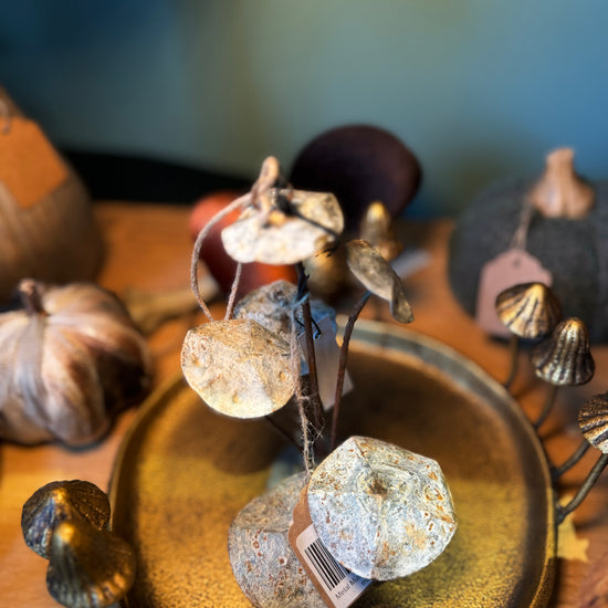 Metal mushroom ornament by Madam Stoltz, displayed on a textured golden plate alongside other autumn decor.