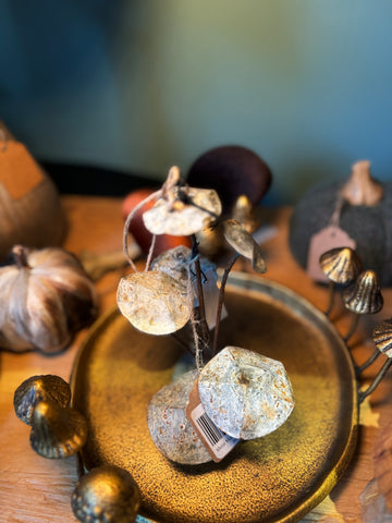 Metal mushroom ornament by Madam Stoltz, displayed on a textured golden plate alongside other autumn decor.