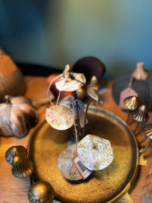 Metal mushroom ornament by Madam Stoltz, displayed on a textured golden plate alongside other autumn decor.