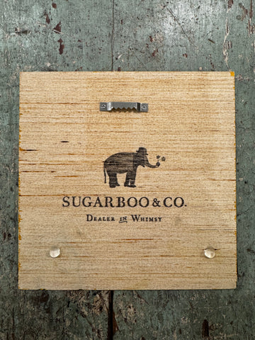 Wood art tile from Sugarboo & Co., featuring an elephant graphic, with a saw-tooth hanger on the back.