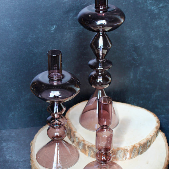 Purple glass modern taper holders by Safavieh displayed on a wood slice platform.