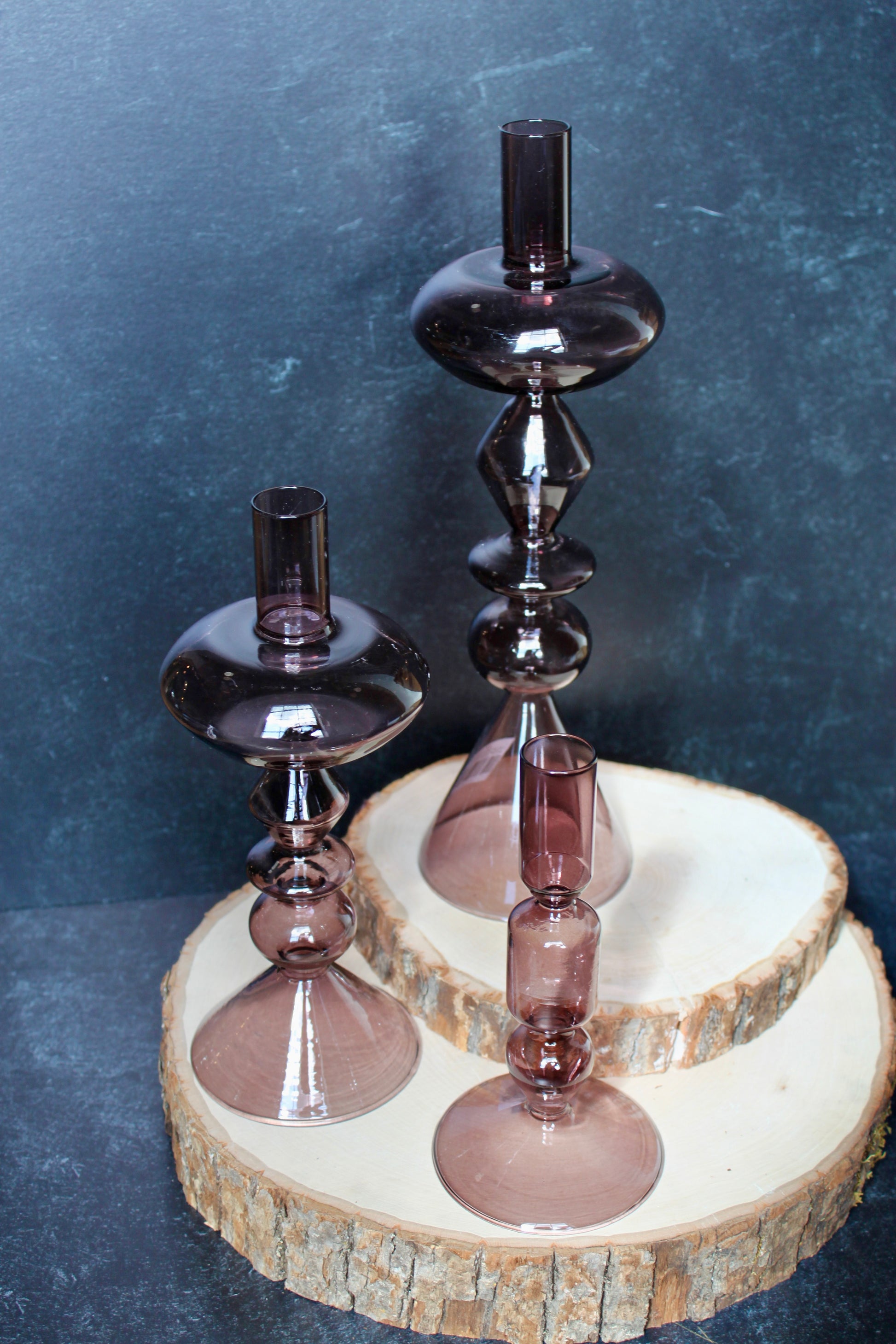 Purple glass modern taper holders by Safavieh displayed on a wood slice platform.