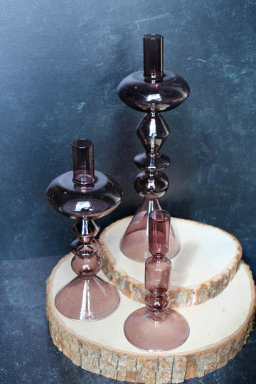 Purple glass modern taper holders by Safavieh displayed on a wood slice platform.