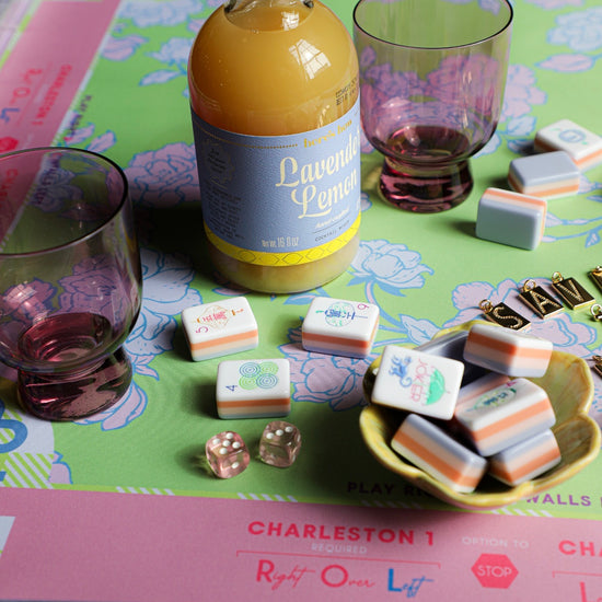 Close-up on a Mahjong class setup with tiles and dice atop a patterned game board.