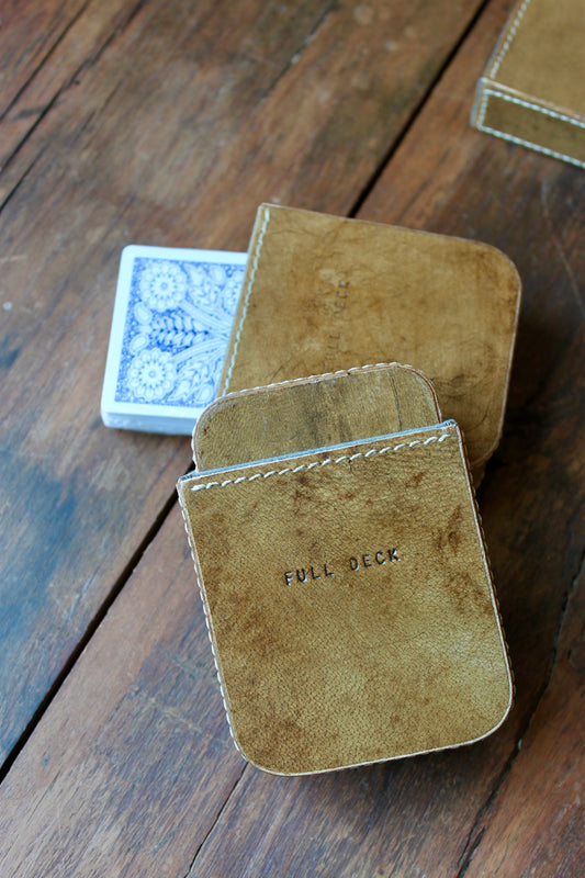 Brown leather card case with playing cards, featuring stitched edges and "FULL DECK" text detail.