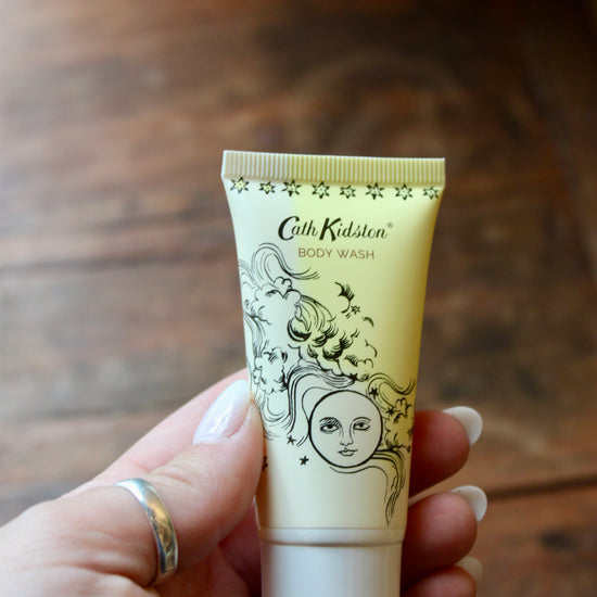 Yellow body wash by Cath Kidston with a decorative celestial illustration being held in a hand.