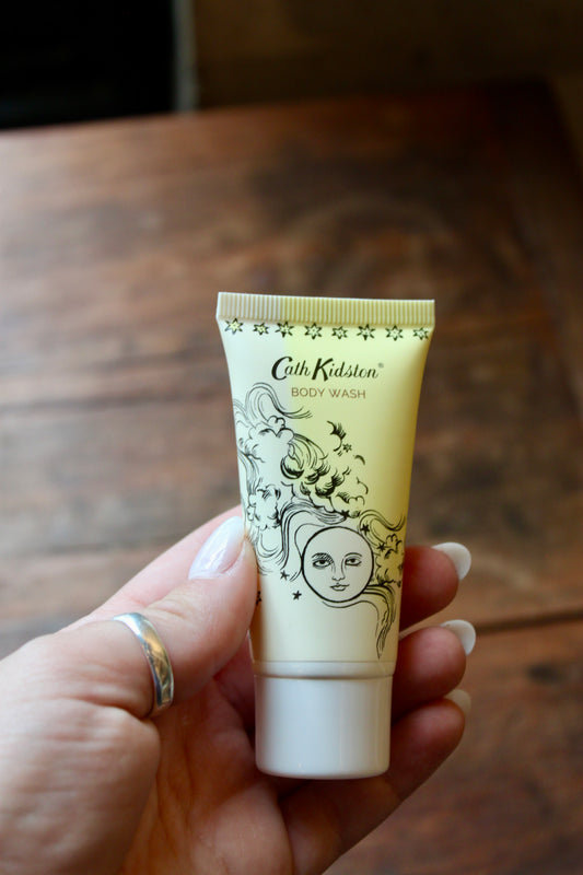 Yellow body wash by Cath Kidston with a decorative celestial illustration being held in a hand.