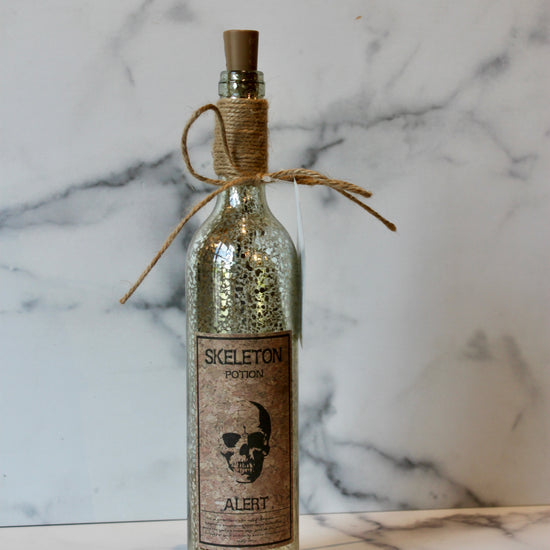 Decorative Halloween potion bottle with cork by Foreside, featuring a distressed silver finish and novelty label.