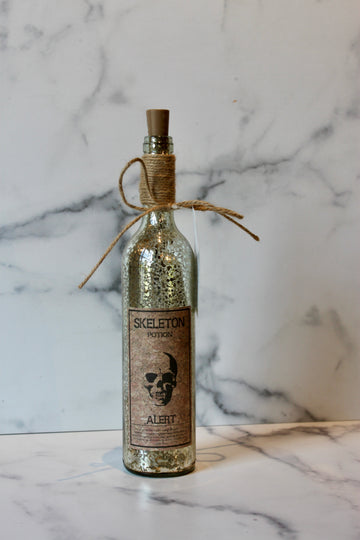 Decorative Halloween potion bottle with cork by Foreside, featuring a distressed silver finish and novelty label.