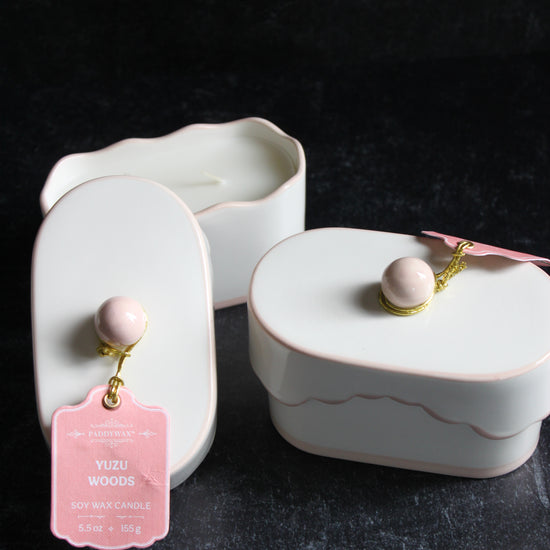 Ceramic candle with lid by Paddywax and a pink gift tag and a golden twine on a dark gray background.