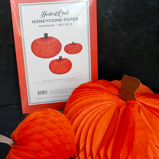 Orange honeycomb paper pumpkins set of 3 by Hester & Cook with paper stems, next to packaging.
