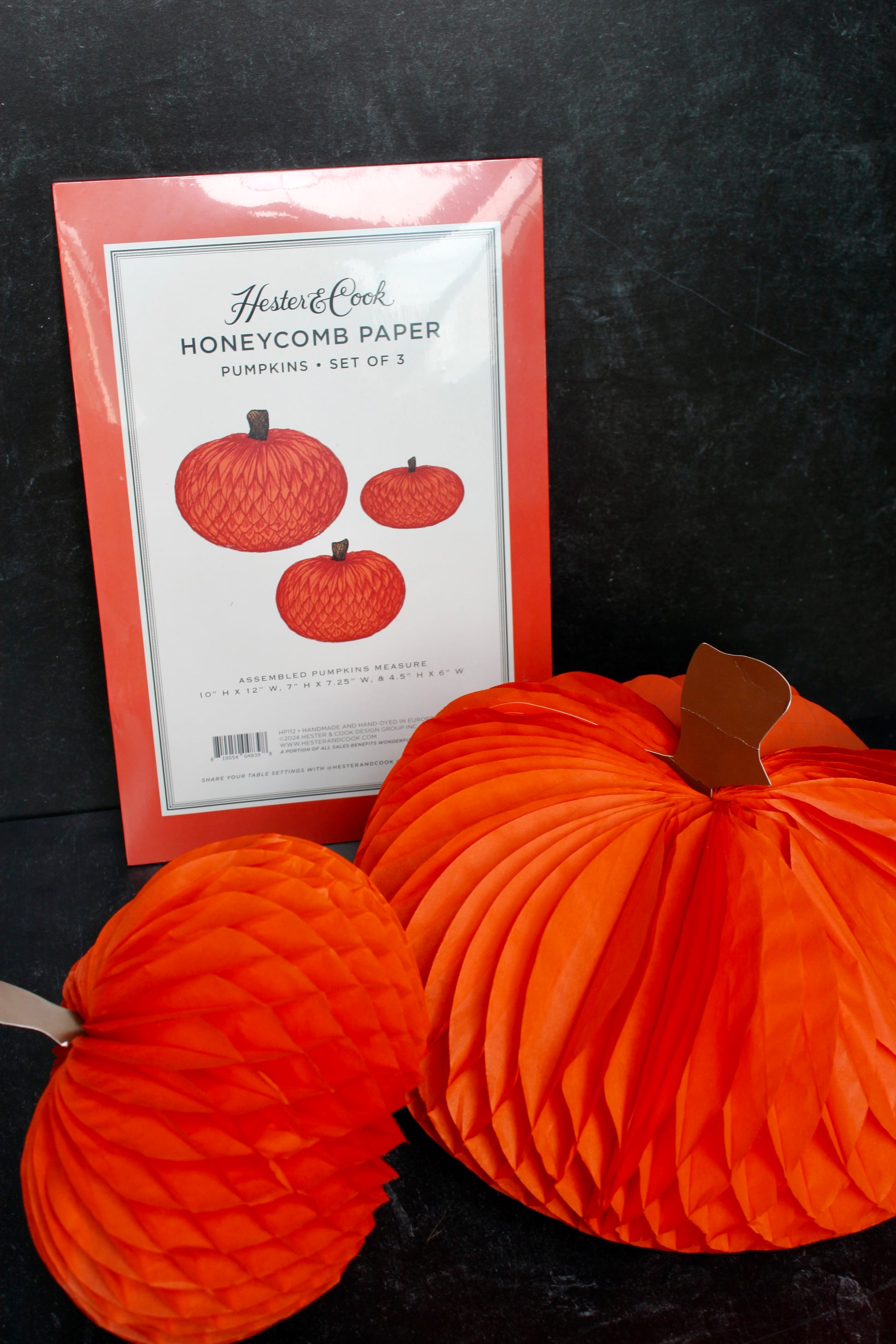 Orange honeycomb paper pumpkins set of 3 by Hester & Cook with paper stems, next to packaging.
