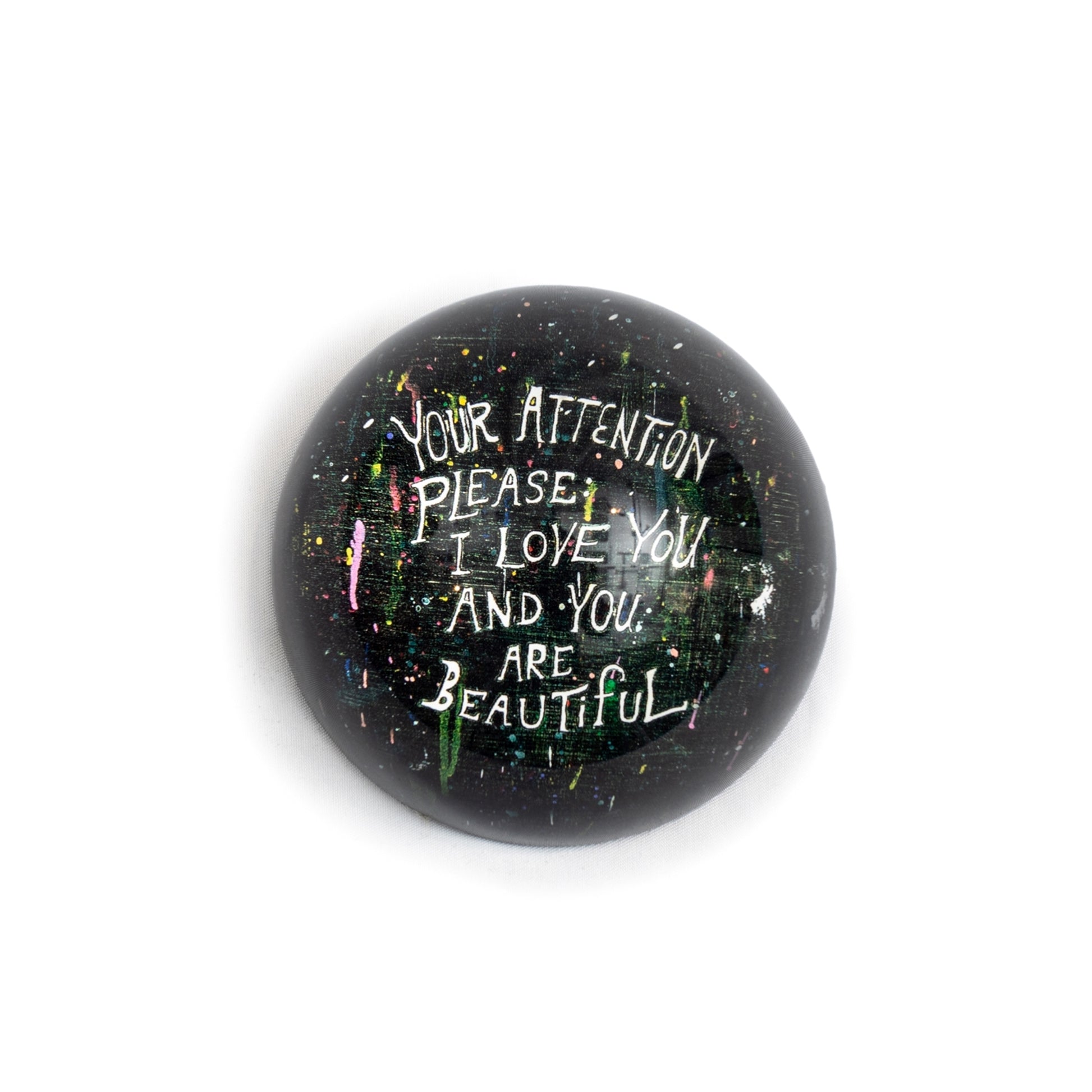 Round paperweight by Sugarboo & Co., featuring splattered colors with a handwritten-style message.
